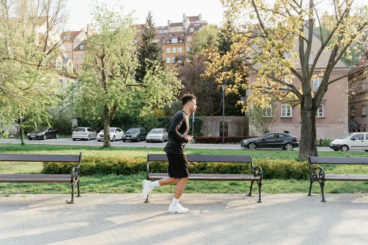 Person jogging outdoors in a park, showing regular physical activity and fitness routine