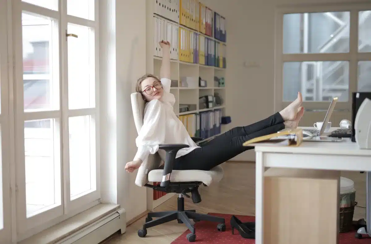 Person performing seated elbow squeeze stretch at office desk to improve spinal alignment.