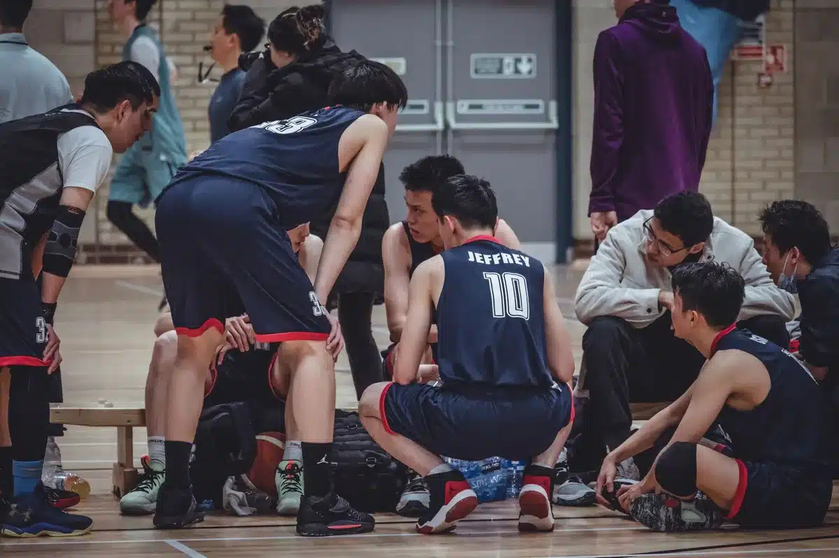 Basketball players in warm-up gear on sideline during game