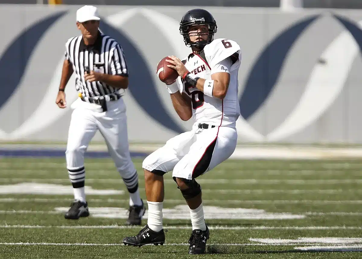 College quarterback dropping back to pass in a stadium during game