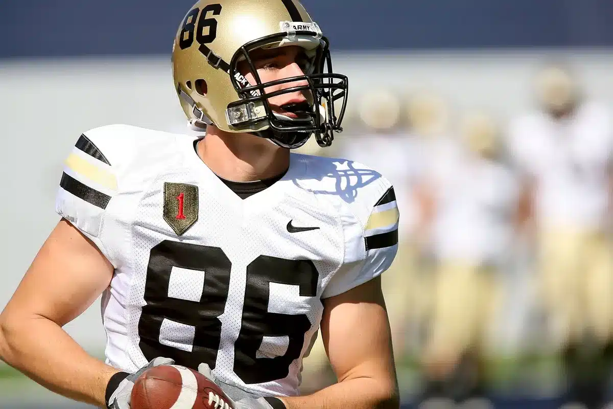 Wide receiver making a contested catch over defender during college game