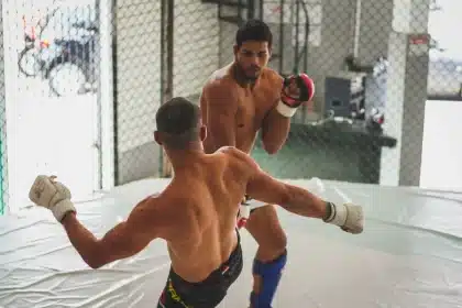 Two anonymous MMA fighters in octagon, one striking stance, one grappling position