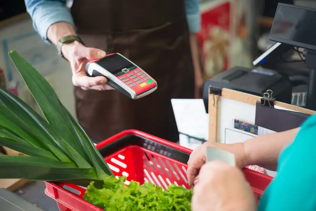 Shopper with full cart at store checkout, illustrating household budget constraints