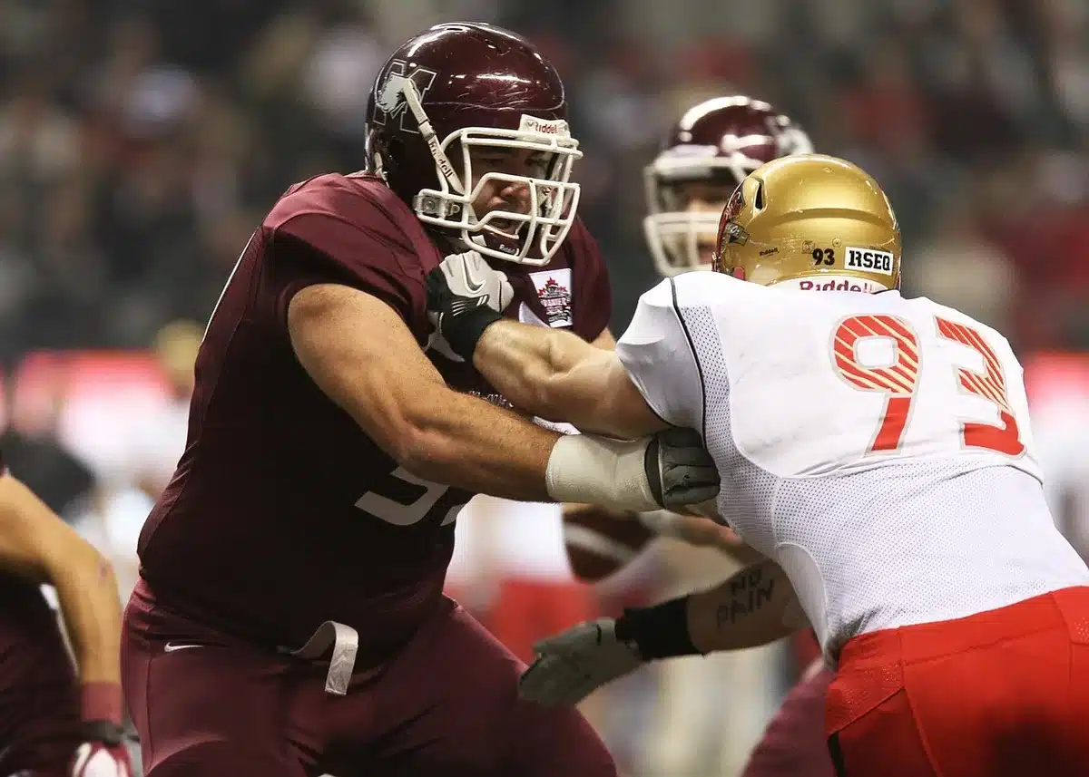 Offensive linemen in formation protecting the quarterback during a college football game.