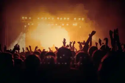 Silhouette of a football helmet on a bench with fans entering a lit stadium
