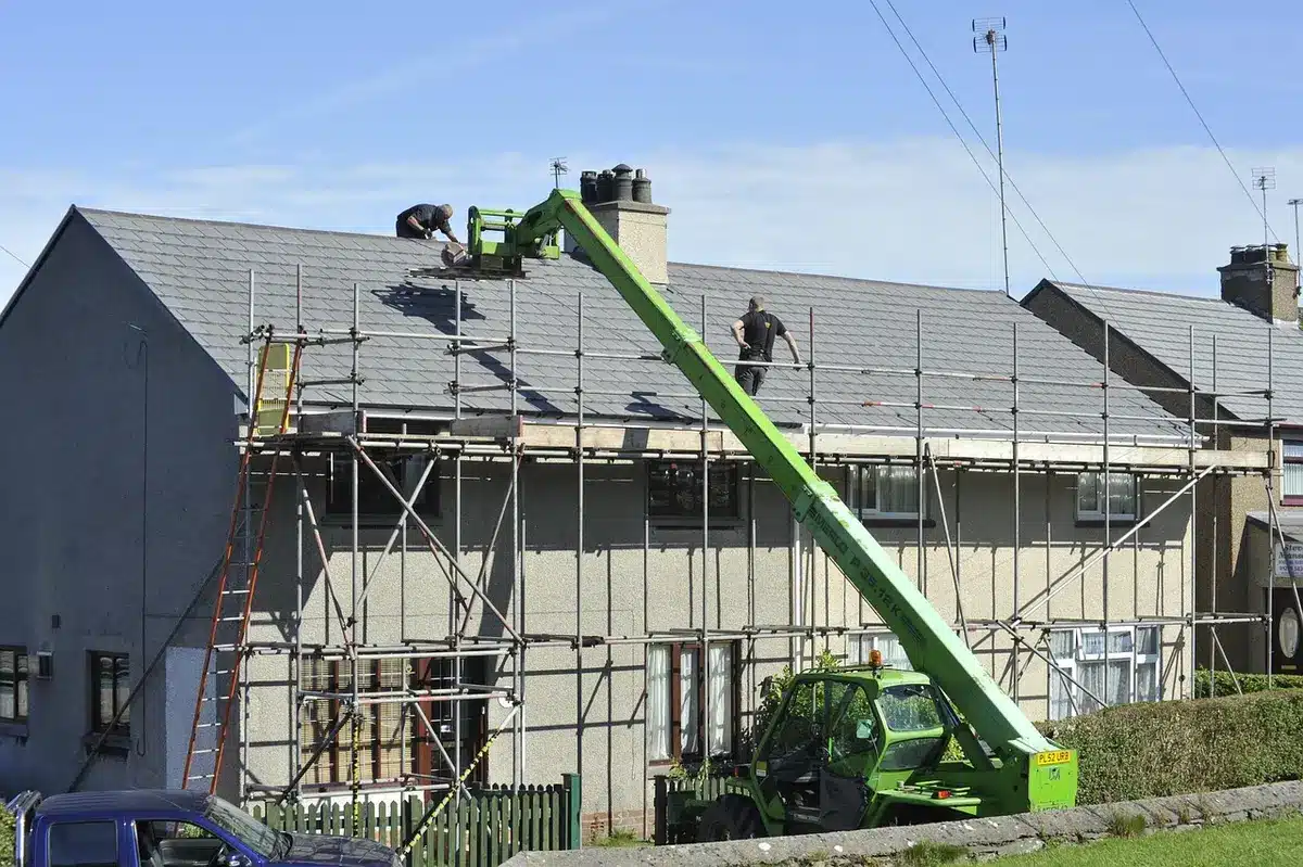 Worker performing roof repairs on residential house exterior