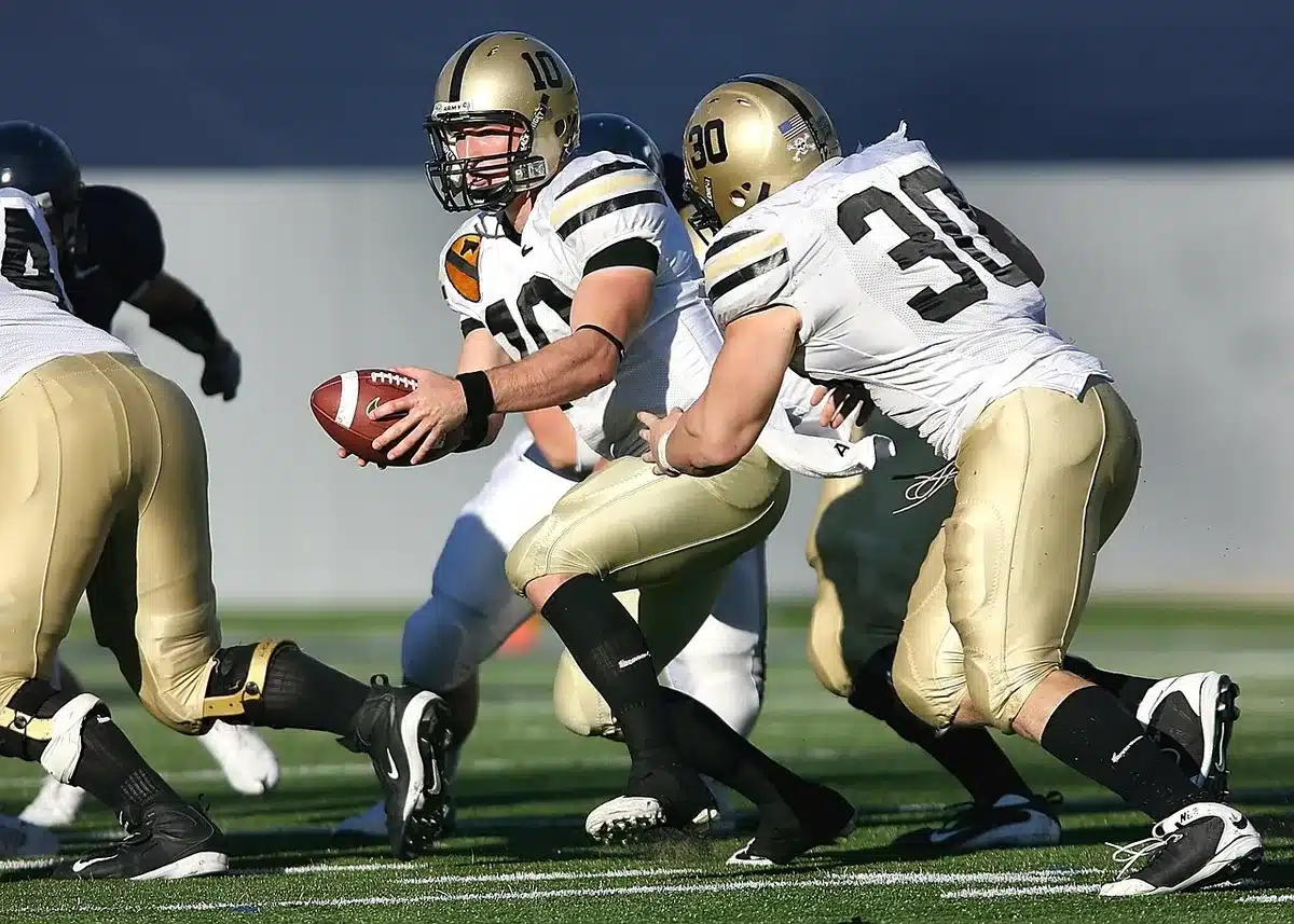 College football running back receiving handoff from quarterback during game