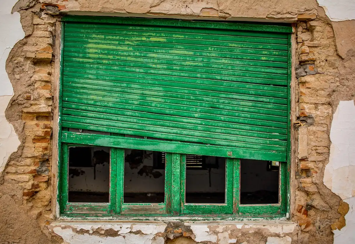 Vacant industrial office building with weathered exterior and boarded windows awaiting demolition