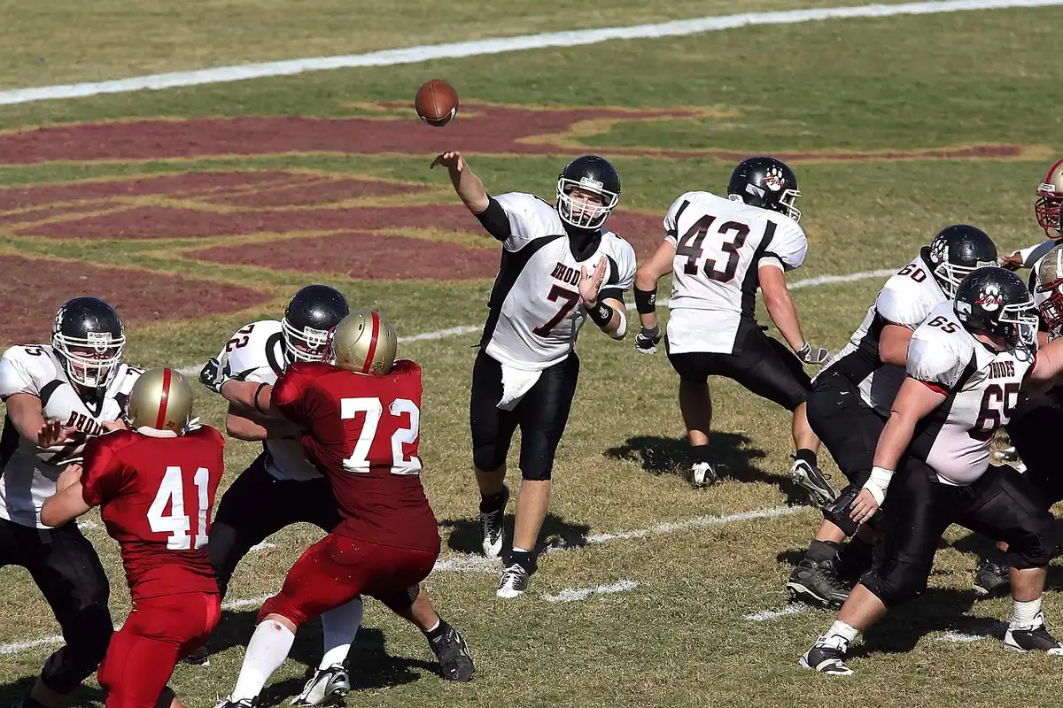 Quarterback releasing a pass under stadium lights
