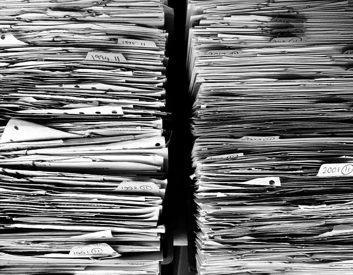 Stack of legal transcripts and court papers on a defense table in a courtroom