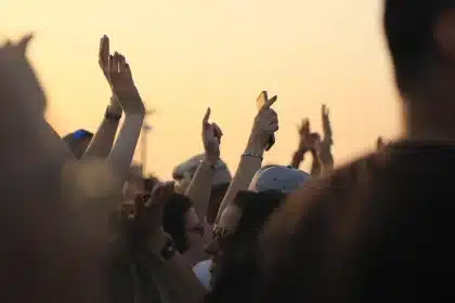 Cage-side view of an octagon edge and raised gloved hands with a cheering crowd